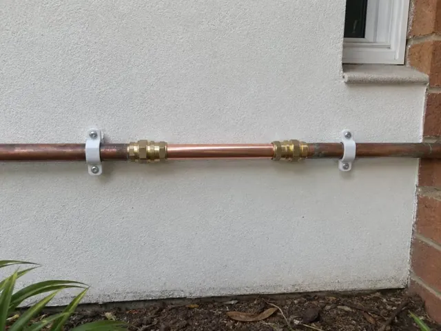 Repaired copper water pipe on a rendered exterior wall beside a brick corner in Blacktown
